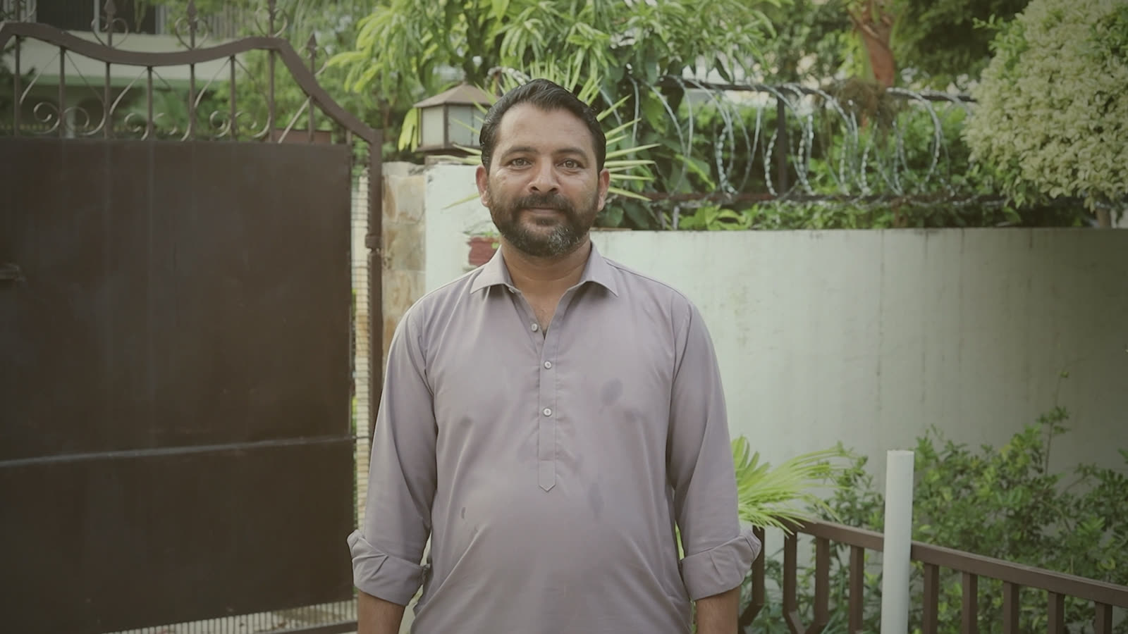 Zulqarnain Haider at the ivy-covered wall by the gate, an easy half-smile